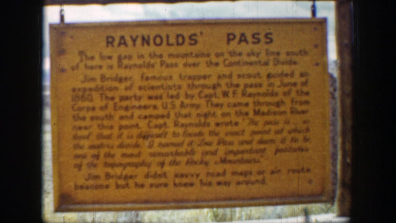 Yellow Reynolds' Pass wooden sign with black text, seen in a soft 8mm close-up.