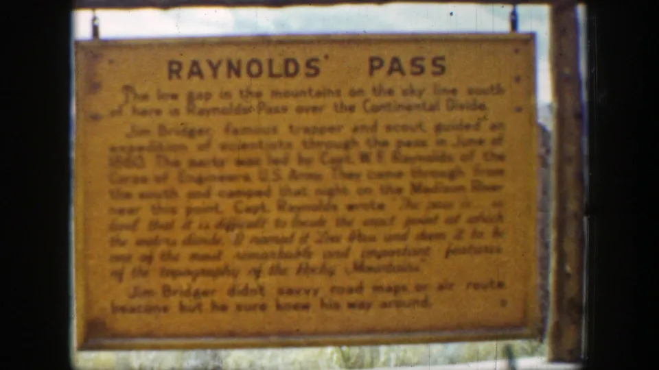 Close 8mm view of the Reynolds' Pass historical sign in Wyoming, showing the title and explanatory text through soft film focus.
