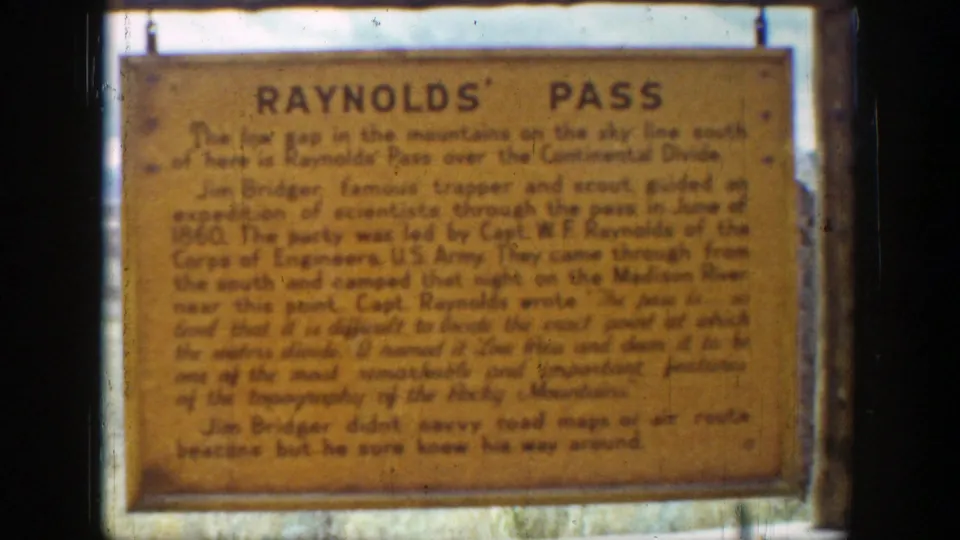 Close 8mm view of the Raynolds' Pass sign in Wyoming, with soft focus and warm aged color.