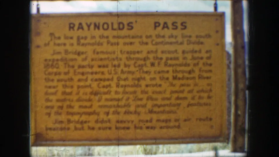 1939 Wyoming 8mm frame showing a close view of the Reynolds Pass historic sign with soft focus, fading color, and dark film borders.
