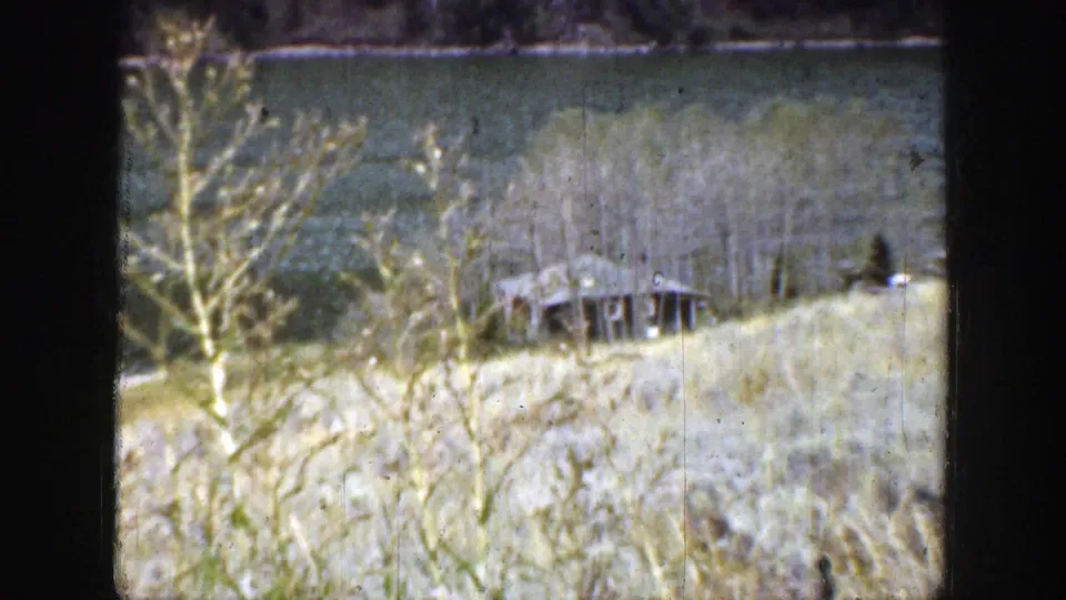 A Wyoming lakeside slope in 1939 shows grass, sparse trees, water, and a small dock-like structure near the shoreline.