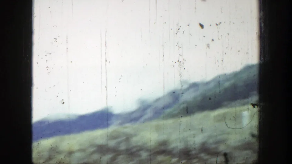 1939 Wyoming landscape frame showing green hills below a darker mountain ridge, with heavy 8mm wear visible.