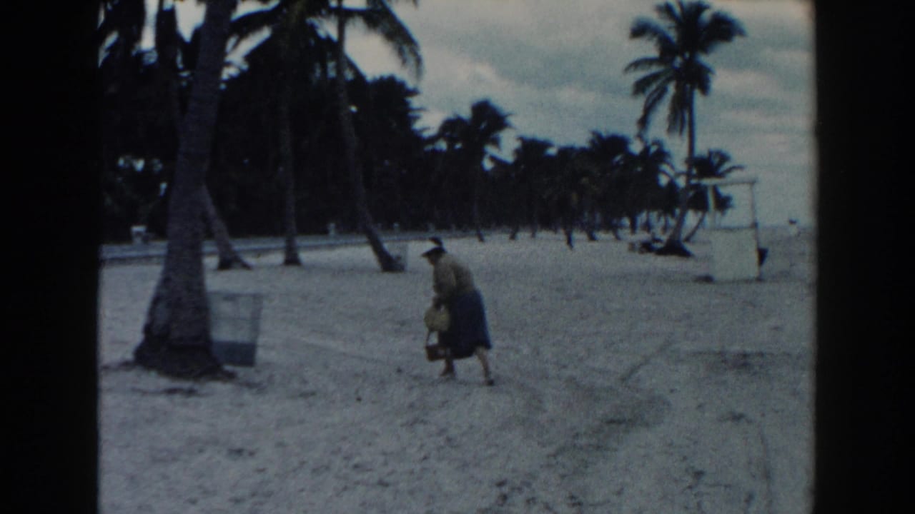 The woman bends down on the Miami beach, appearing to pick up an object from the sand beside her basket.