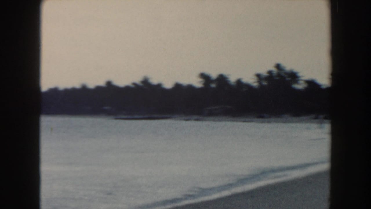 1960 Miami home-movie view of calm bay water, a distant low shoreline, and dark frame edges from the 8mm scan.