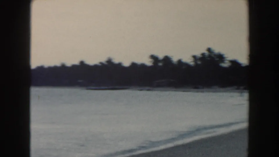 1960 Miami home-movie view of calm bay water, a distant low shoreline, and dark frame edges from the 8mm scan.