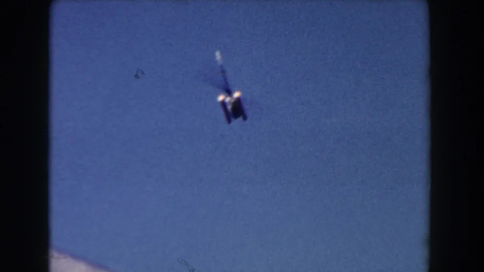 1960 Miami 8mm frame showing a distant blurry aircraft or helicopter against a blue sky.