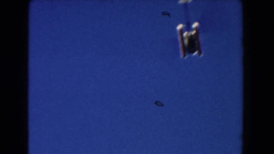 Low-angle 1960 Miami frame showing the underside of a helicopter high against a saturated blue sky.