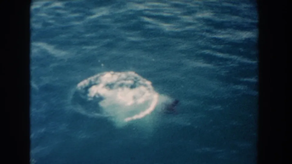 1960 Miami home-movie frame showing blue water and a circular splash or wake, with no clearly identifiable person visible.