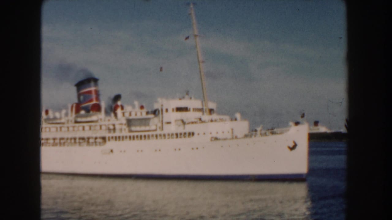 White passenger ship with red and blue smokestack emitting dark smoke.
