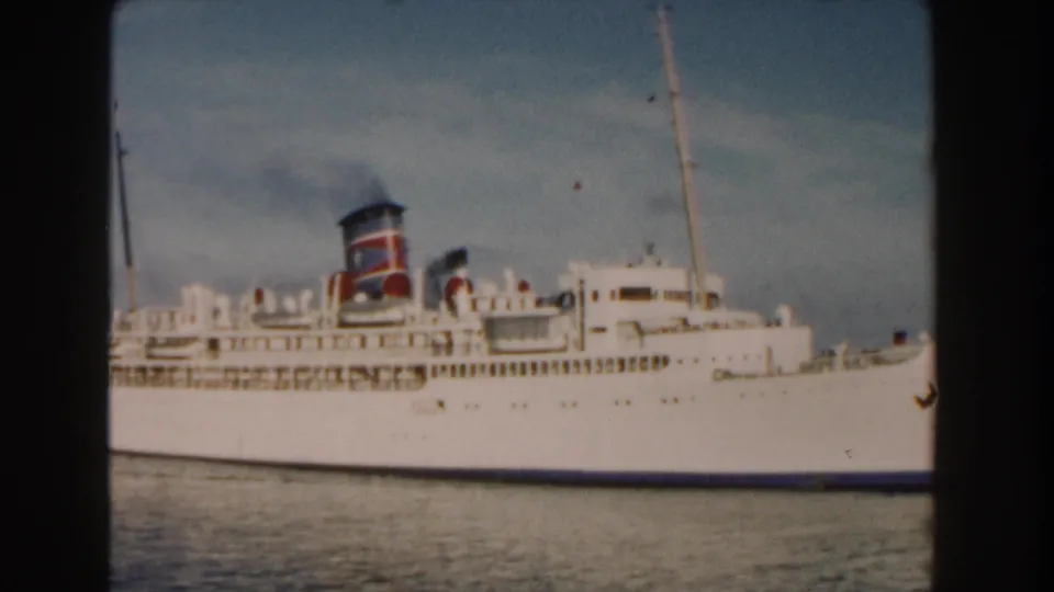 A closer 1960 Miami harbor view shows the white passenger ship broadside, with funnel smoke, deck details, and soft 8mm color.