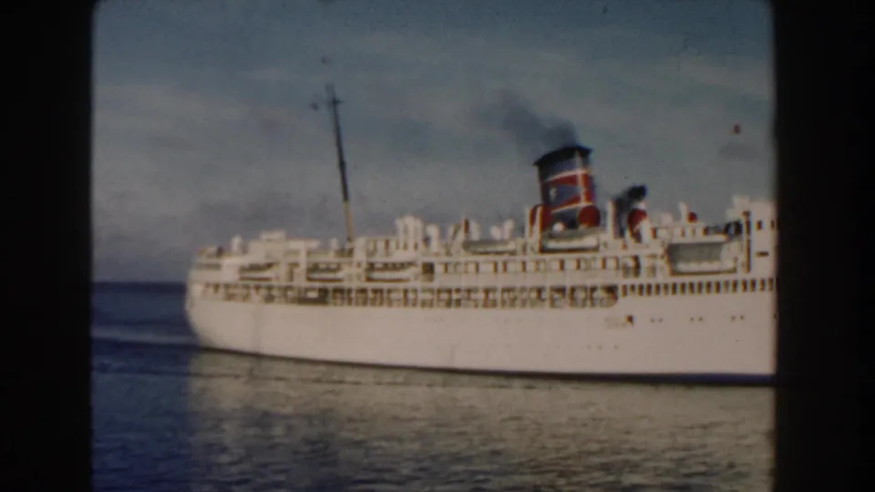 1960 Miami-area home-movie frame of a white ocean liner sliding across the frame on blue water.