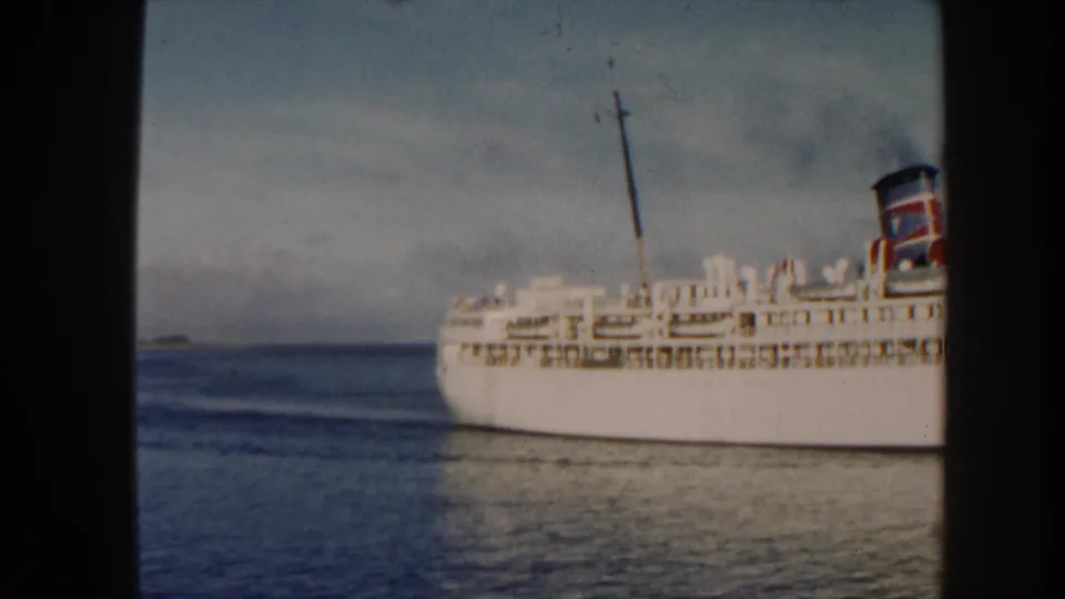 1960 Miami-area home-movie frame of the liner exiting the shot, with water and pale sky filling the scene.