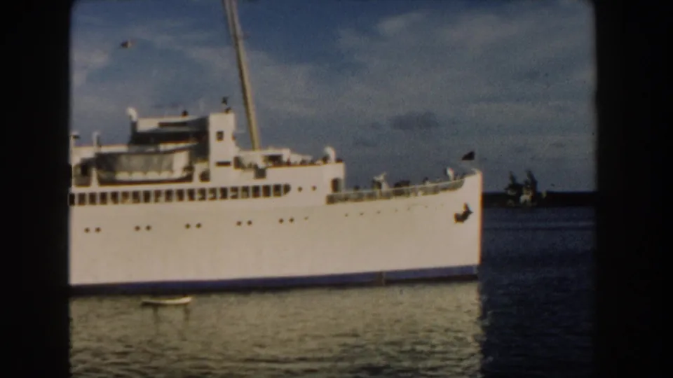 1960 Miami 8mm frame showing the midsection of a large white passenger ship, including rows of windows, upper deck structures, and calm water below.