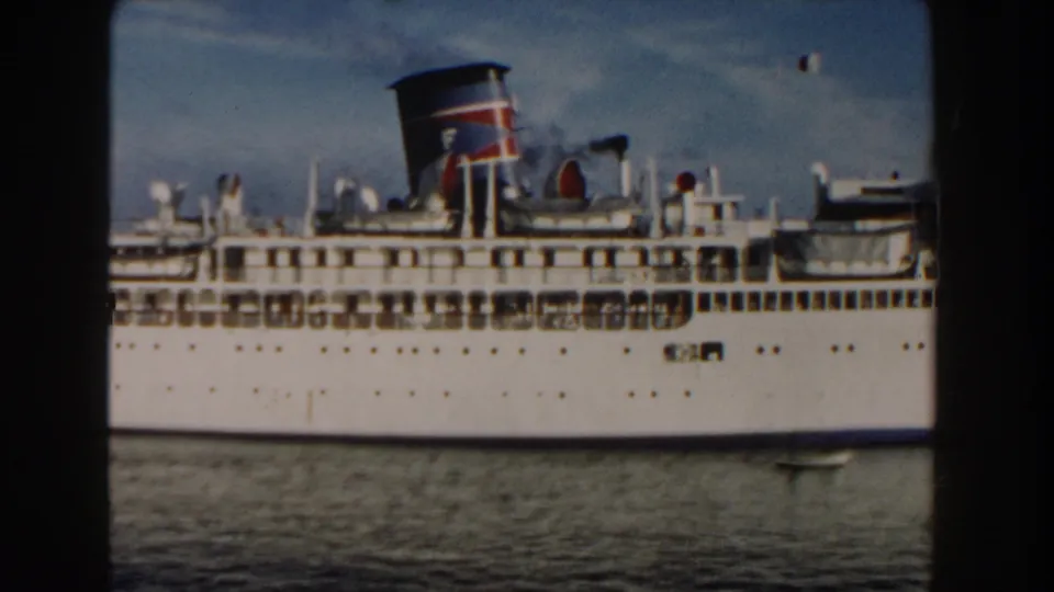 1960 Miami 8mm frame with a closer look at the passenger ship's upper decks, colored funnel, white hull, and waterline.