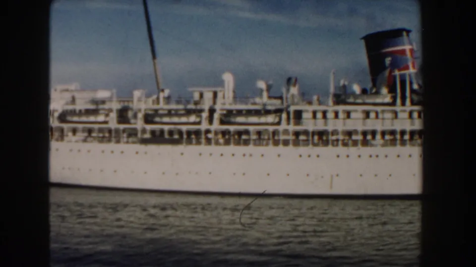 1960 Miami-area 8mm frame of a white cruise ship moving across calm blue water, with deck railings, funnel markings, and film gate edges visible.
