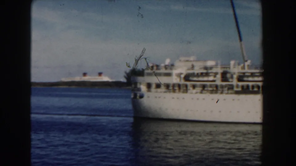 1960 Miami-area 8mm frame showing the forward section of a white passenger ship, calm water, distant vessel, and soft home-movie exposure.
