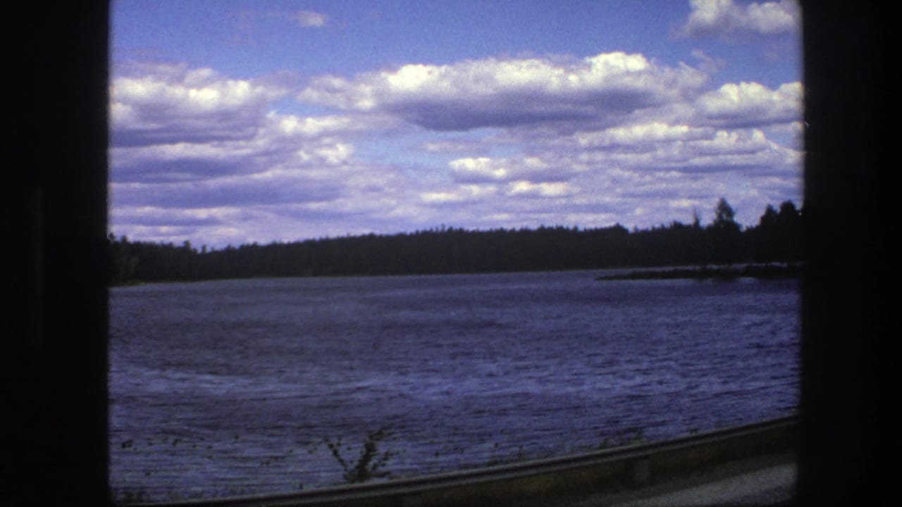 Lake and forested shoreline framed by dark vehicle-window edges.
