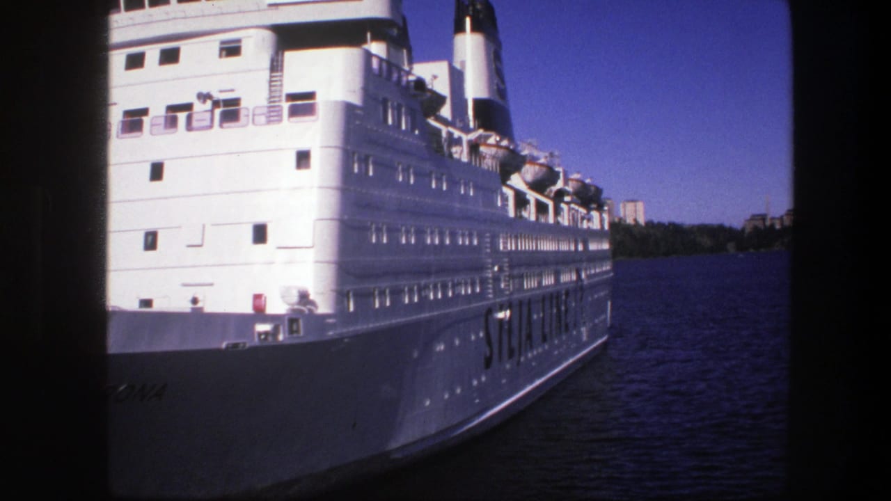 1975 Sweden 8mm frame showing a large white passenger ship on a river, with lifeboats, deck windows, distant trees, and buildings.