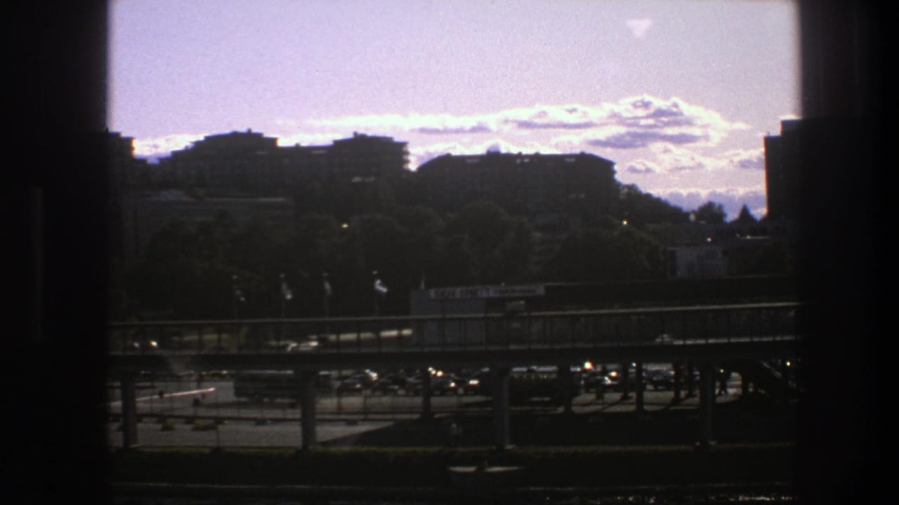 Distant buildings and roadway traffic viewed through dark vertical window edges.