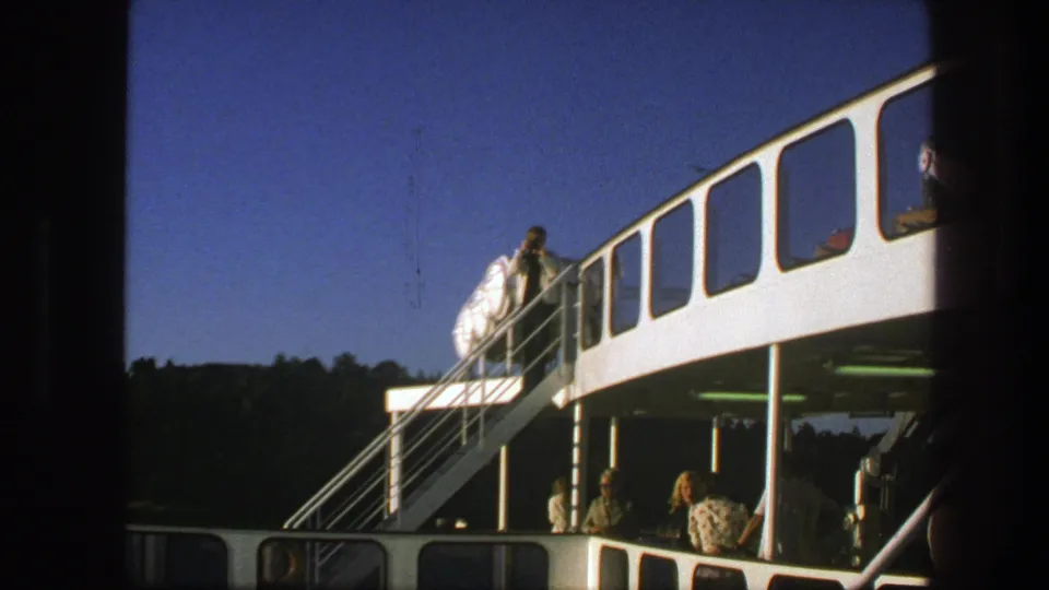 1975 Sweden ferry scene showing a man in a white shirt on the exterior stairs and passengers on the lower deck.