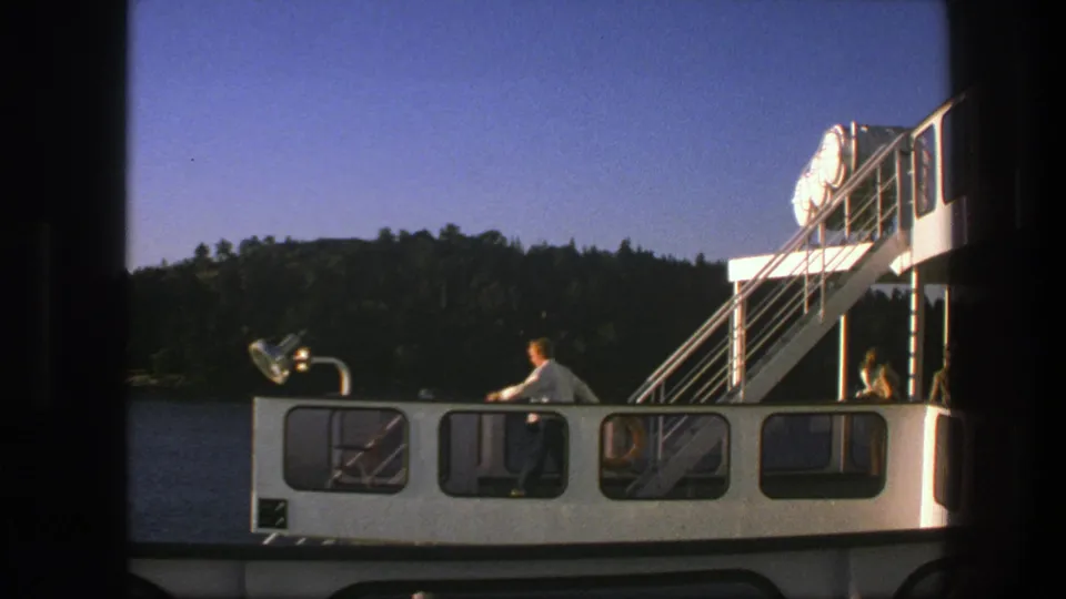 1975 Sweden 8mm frame showing the ferry side, exterior stairway, deck windows, and a man near the railing.