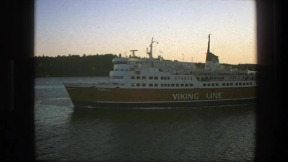 The Viking Line ferry is seen broadside, with its yellow hull and white decks crossing calm water in the 1975 Sweden clip.