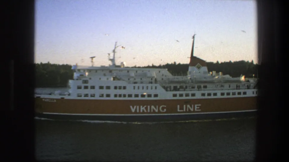 A softly exposed 8mm view of the Viking Line ferry passing through Swedish waters, with the ship partly framed by dark foreground edges.
