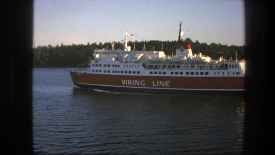The ferry is seen in clearer side view in 1975 Sweden, with Viking Line branding, calm water, and a tree-lined shore in warm light.