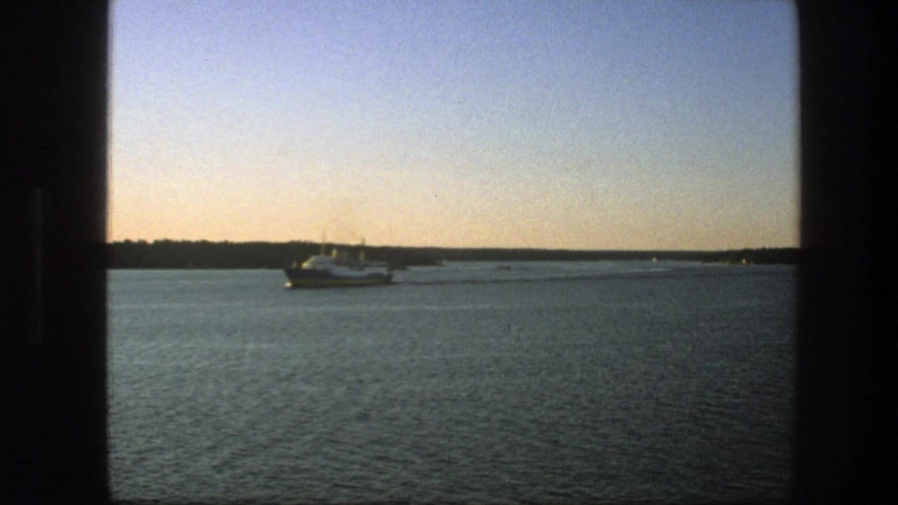 1975 Sweden 8mm frame showing a white passenger ship on calm water under a pale sky, with dark window-like edges in the foreground.