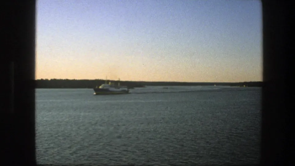 1975 Sweden 8mm frame showing a white passenger ship on calm water under a pale sky, with dark window-like edges in the foreground.