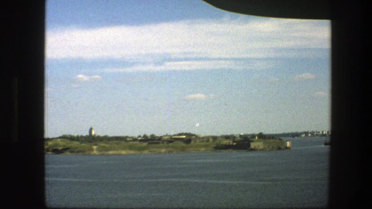 Island shoreline seen across calm water through a dark window frame.