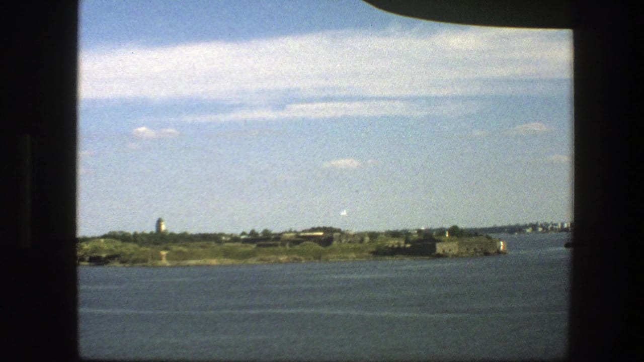 Distant island with tower and stone buildings beyond open water.