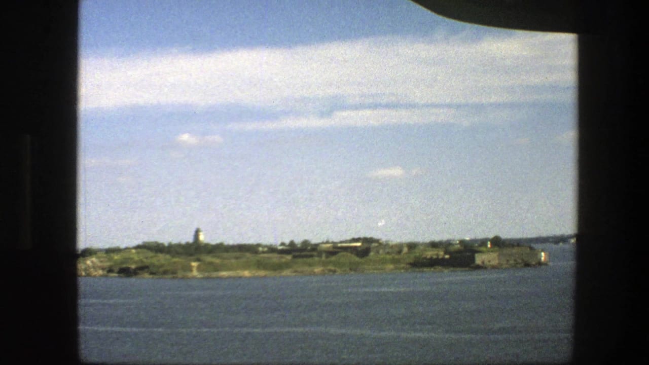 Island shoreline and low buildings seen through a dark window frame.