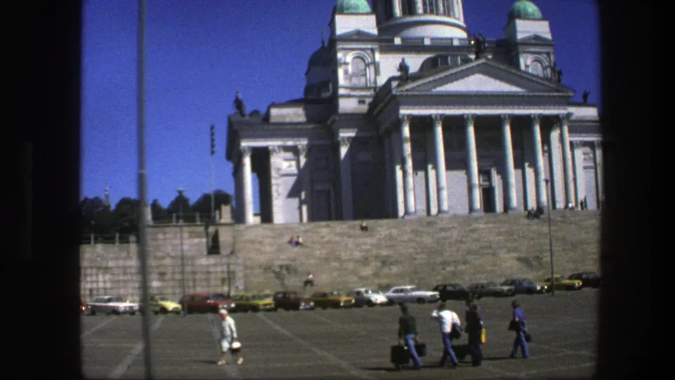 A wider 8mm view includes the cathedral facade, broad steps, parked period cars, and several pedestrians crossing the open square.