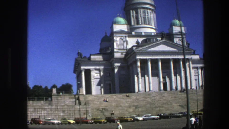 The final frame holds on the white domed landmark from the square, with cars lined below and distant visitors near the steps.