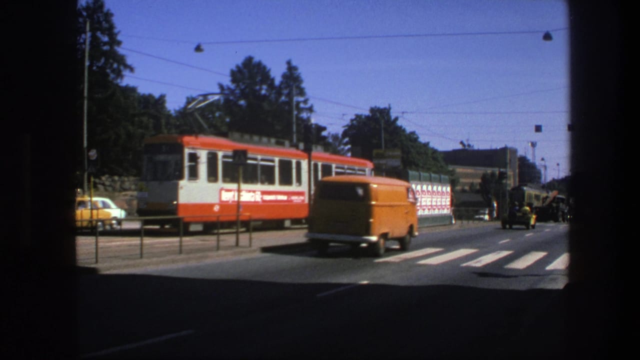 Orange van passes in front of a red-and-white tram at a zebra crossing.