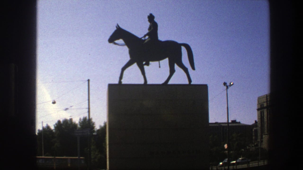 Silhouetted horse-and-rider statue on a tall pedestal against a blue sky.