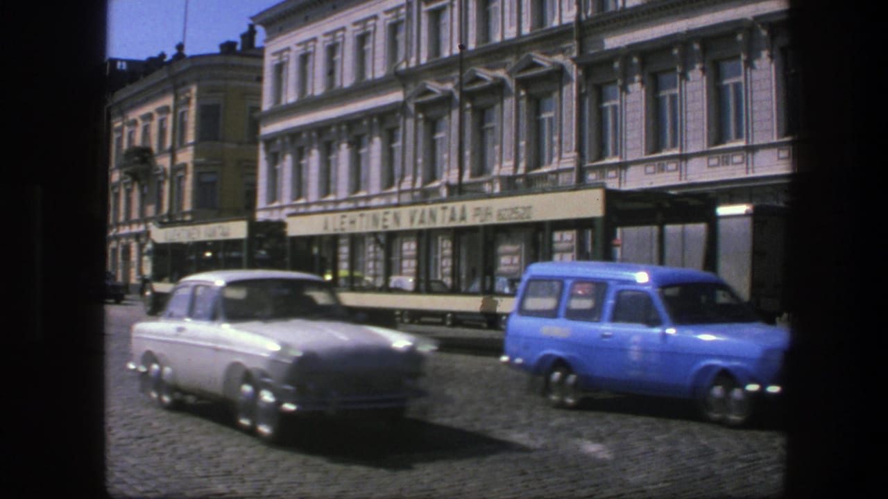 White sedan and bright blue wagon drive beside a streetcar on a city street.