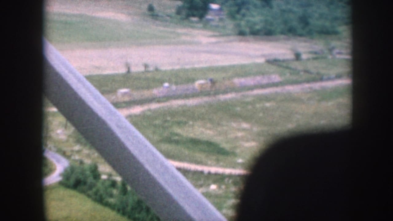 1958 Nebraska aerial view showing patchwork farmland, rural roads, and scattered buildings through an aircraft window.