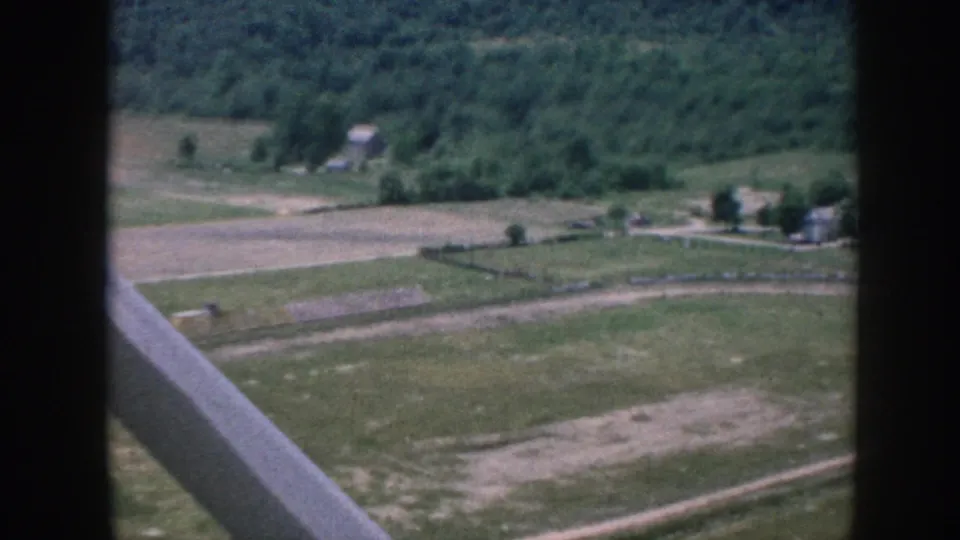 1958 Nebraska aerial farmland view with open fields, scattered farm buildings, tree lines, and aircraft window structure.