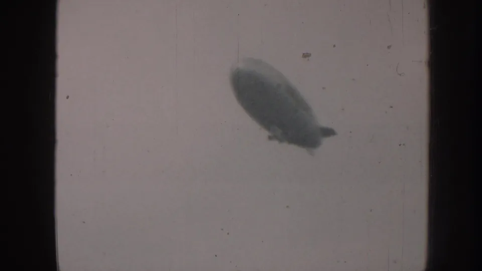 The airship-like craft is seen larger and softly focused against a plain pale sky in the Nebraska 1958 clip.