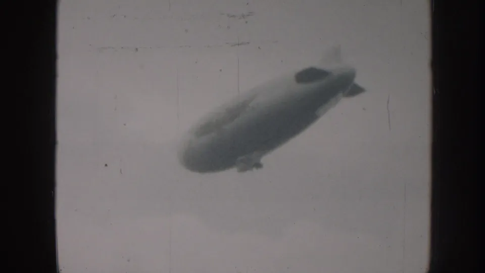 1958 Nebraska 8mm frame showing the airship lower in the frame with soft focus and visible film wear.