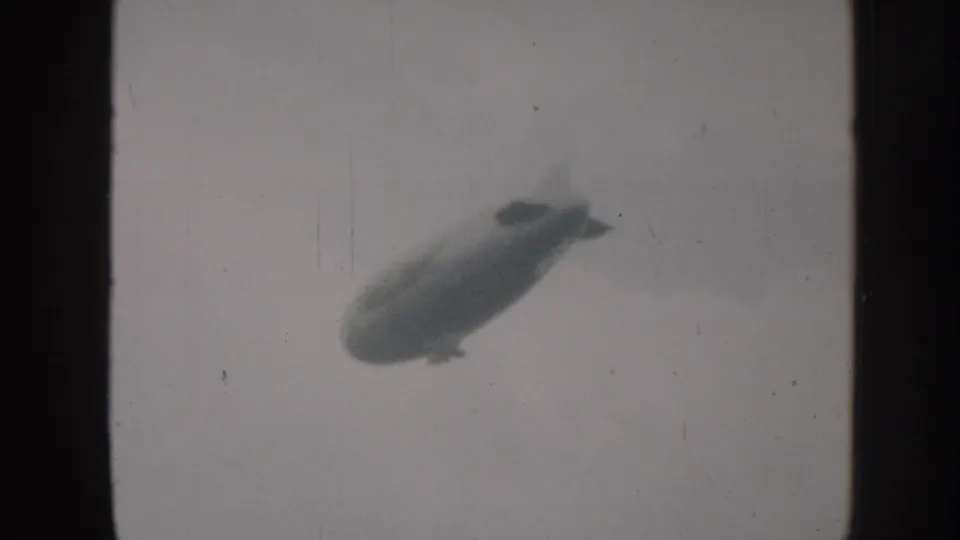 A third view shows the blimp as a soft, dark shape in the cloudy Nebraska sky, consistent with 1958 8mm footage.