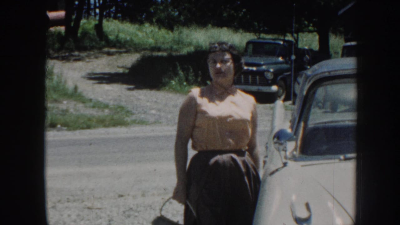 Woman stands beside a white vintage car on a rural road.