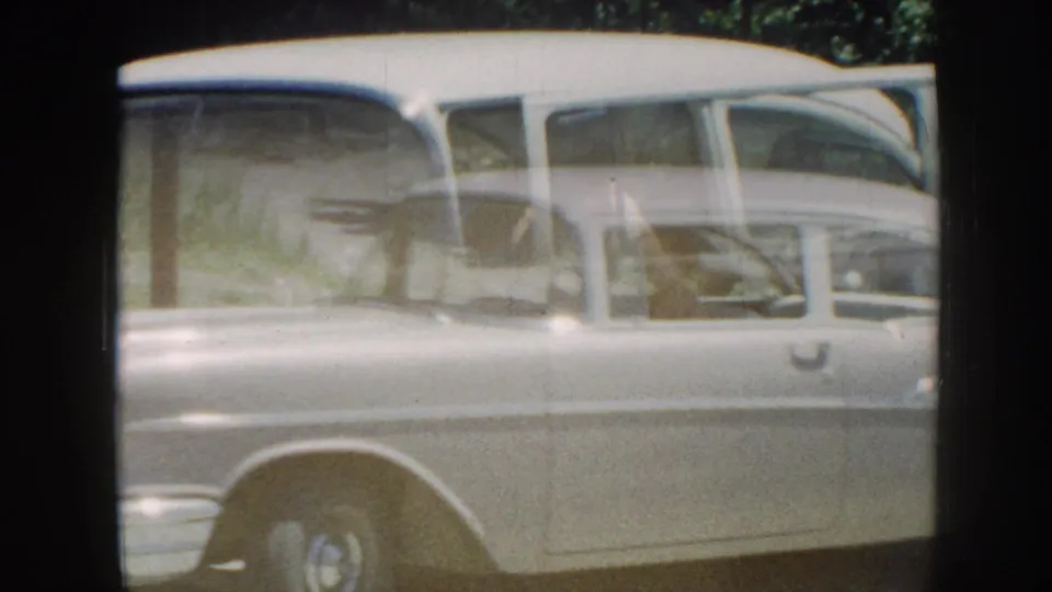 The gray sedan passes close to the camera, with soft 8mm motion blur and reflections across its side windows.