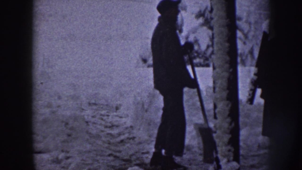 The man stands in profile with a shovel beside a tree trunk in a snowy Nebraska outdoor scene from 1958.