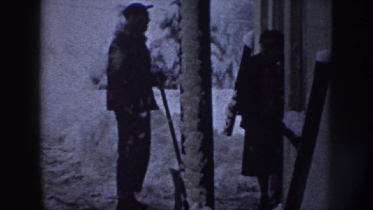 A 1958 Nebraska winter frame shows two people in heavy coats standing in snow, with one holding a shovel-like tool.