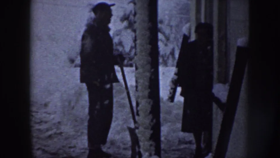 A 1958 Nebraska winter frame shows two people in heavy coats standing in snow, with one holding a shovel-like tool.