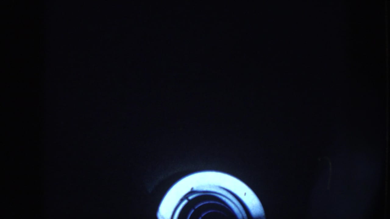Dark barn interior with a bright circular light or lens flare near the lower edge.