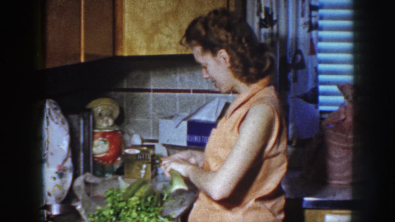 Woman looks down while handling vegetables at a kitchen counter.